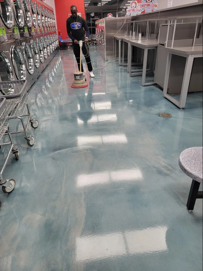 Crew machine-scrubbing a retail store aisle floor to a wet shine