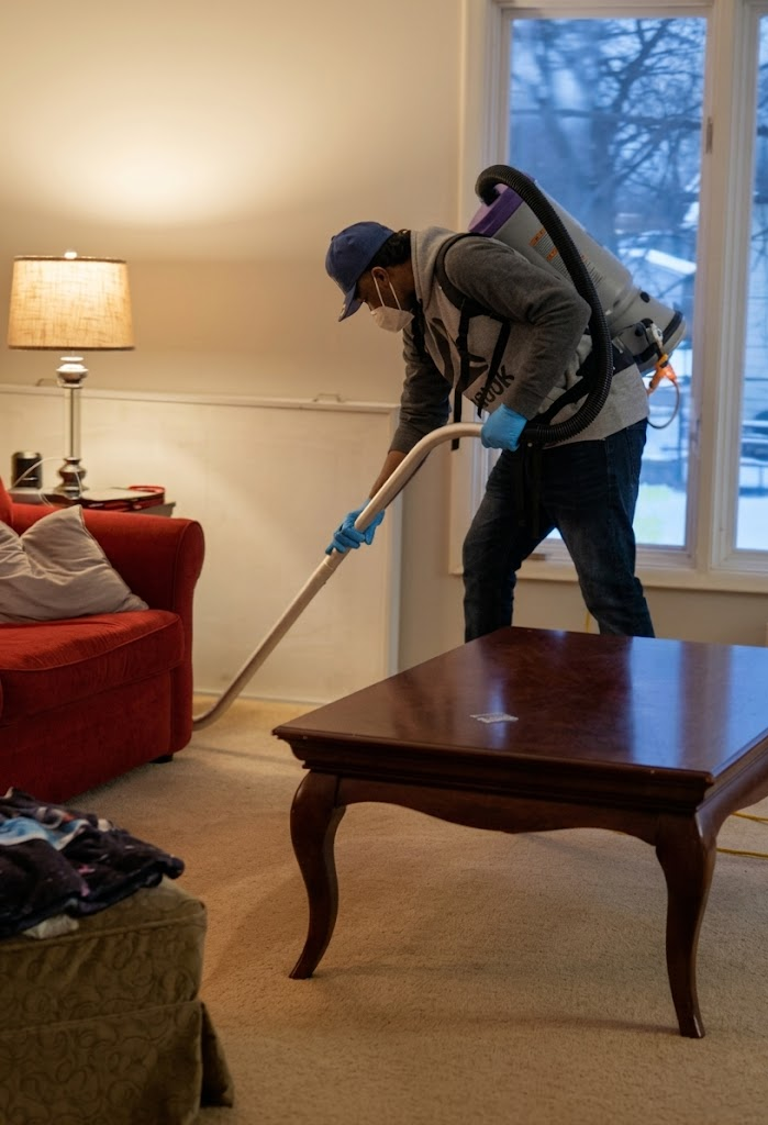 Crew member detail-vacuuming carpet edges around furniture