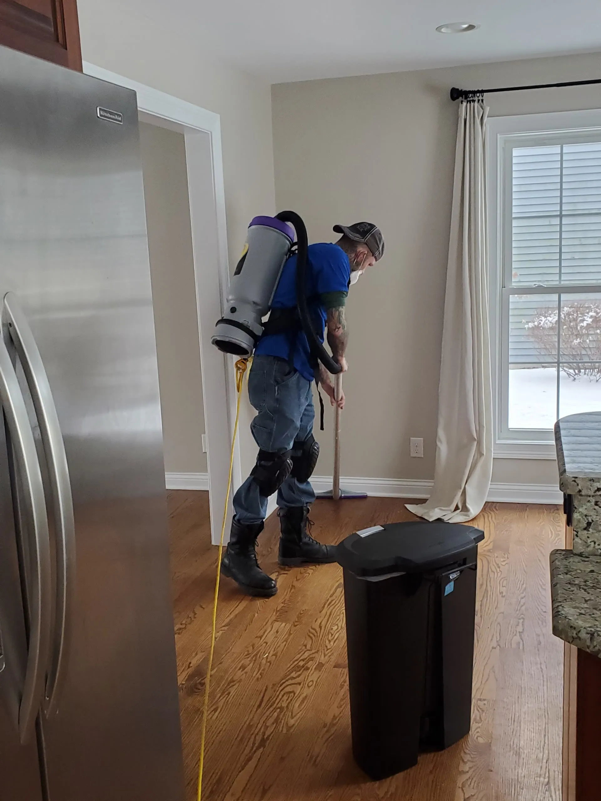 Clean King crew member vacuuming a client's home with a backpack vacuum